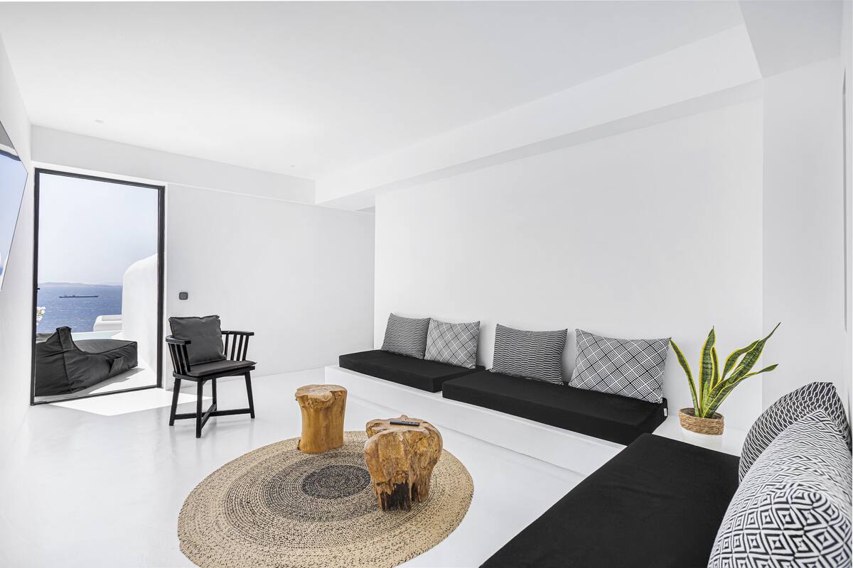 Una sala de estar moderna con un sofá, un sillón, una mesita de centro y vista al mar.