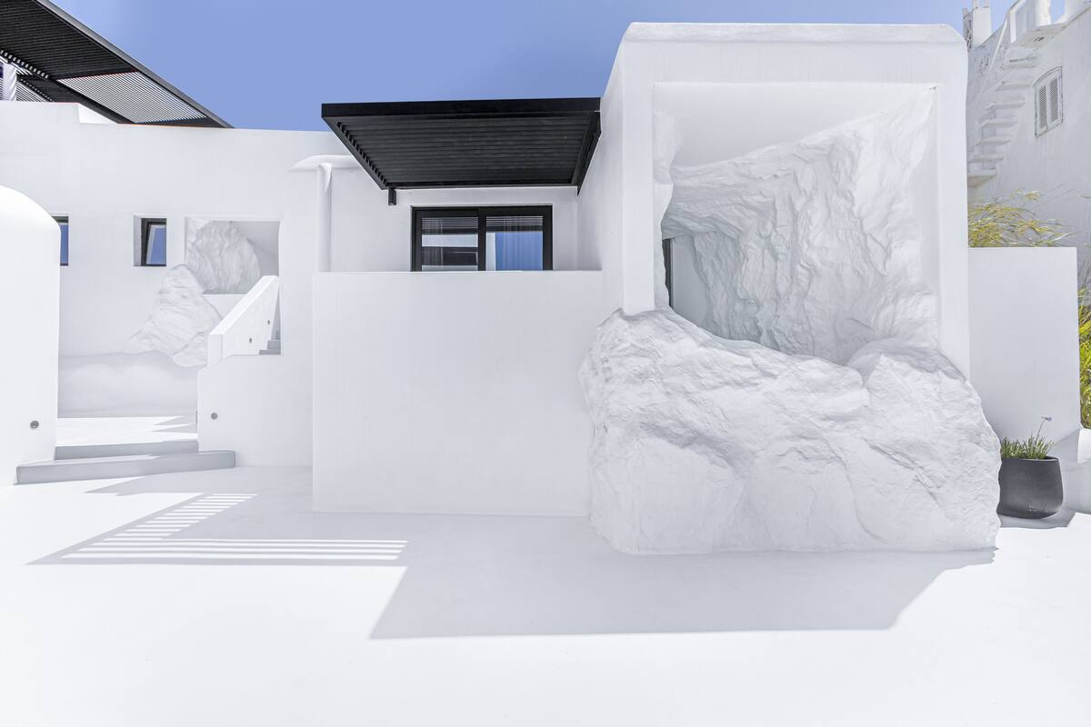 Diseño arquitectónico moderno con una imponente roca blanca y techo negro.