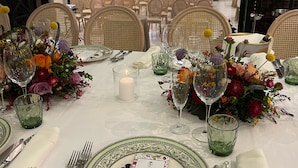 Un elegante montaje para comedor con mesas redondas, manteles blancos y centros de mesa florales.