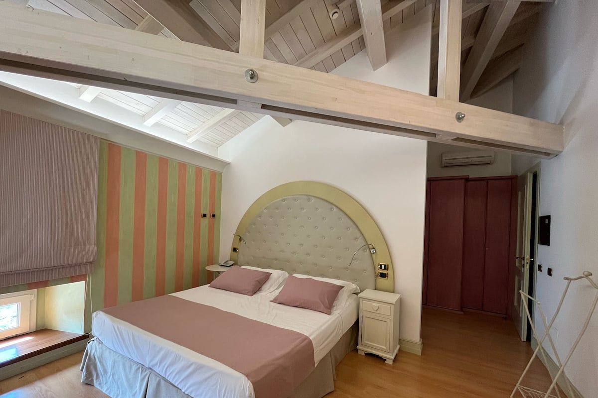 Ein Schlafzimmer mit einem großen Bett, einem Nachttisch, einem Kleiderschrank und einem Oberlicht.