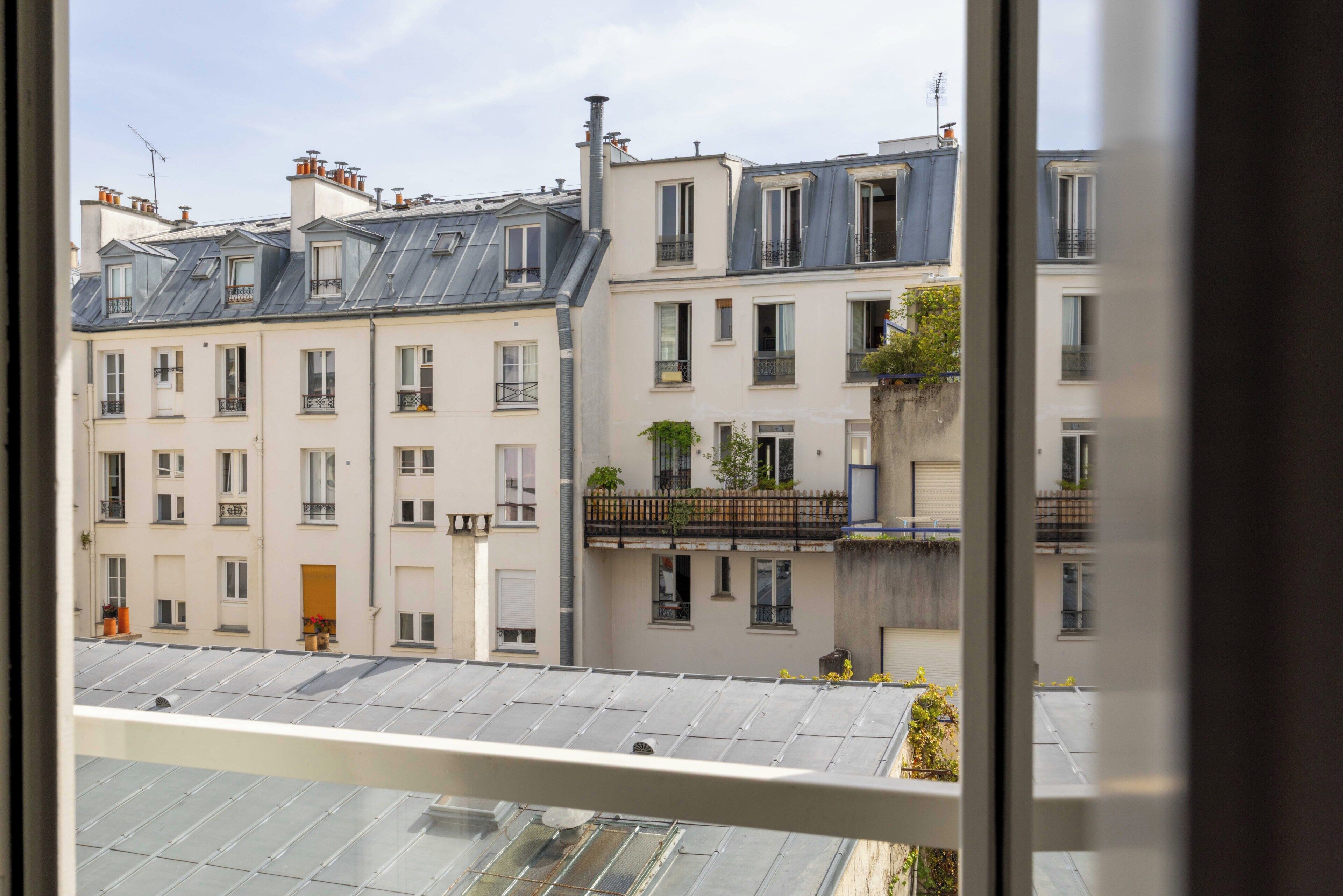 A row of multi-story buildings with balconies, some with plants, and a clear sky.