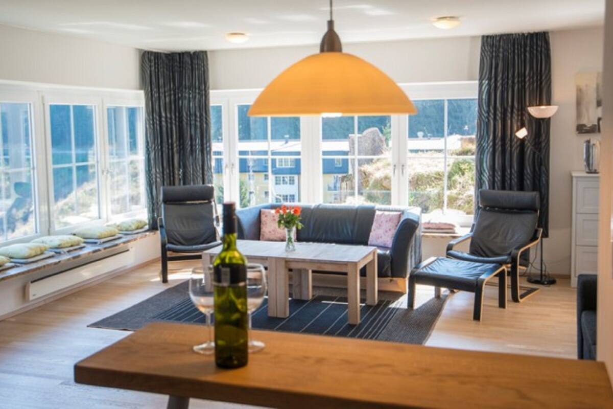 A modern living room with a sofa, chairs, a coffee table, and a large window.