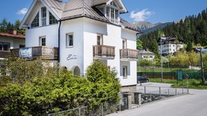 Un edificio a due piani con facciata bianca, balconi e un cartello con su scritto "Alpenreise".