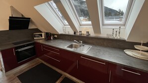 Una cucina con finestra a lucernario, forno a microonde, lavello e fornello.