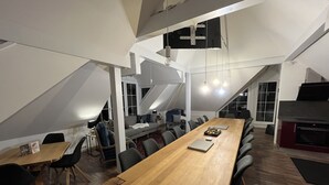 Una sala conferenze moderna con un lungo tavolo in legno, sedie nere e un forno a incasso.