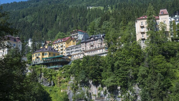 Un hotel con varias construcciones en una ladera, rodeado de bosque denso.