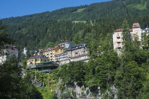 A hotel with multiple buildings on a hillside, surrounded by dense forest.