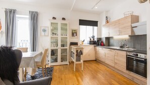 Una cocina moderna con armarios de madera, un comedor con mantel a rayas y vistas al exterior a través de amplios ventanales.