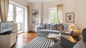 Un salón moderno con un sofá gris, una mesa de centro, un televisor y una cita motivacional enmarcada en la pared.