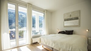 A bedroom with a large bed, a view of mountains through a sliding glass door, and a framed picture on the wall. - Haus Lothringen (Bad Gastein)