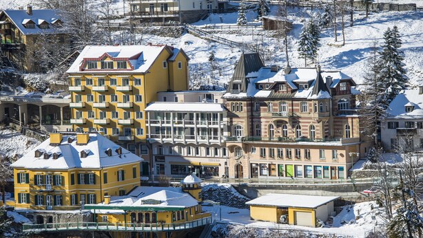 A snow-covered town with a variety of buildings including a yellow hotel with balconies and a historic building with a turret. - Haus Lothringen (Bad Gastein)
