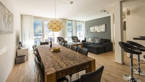 A modern living room with a dining area, large windows, and a city view. - Haus Lothringen (Bad Gastein)