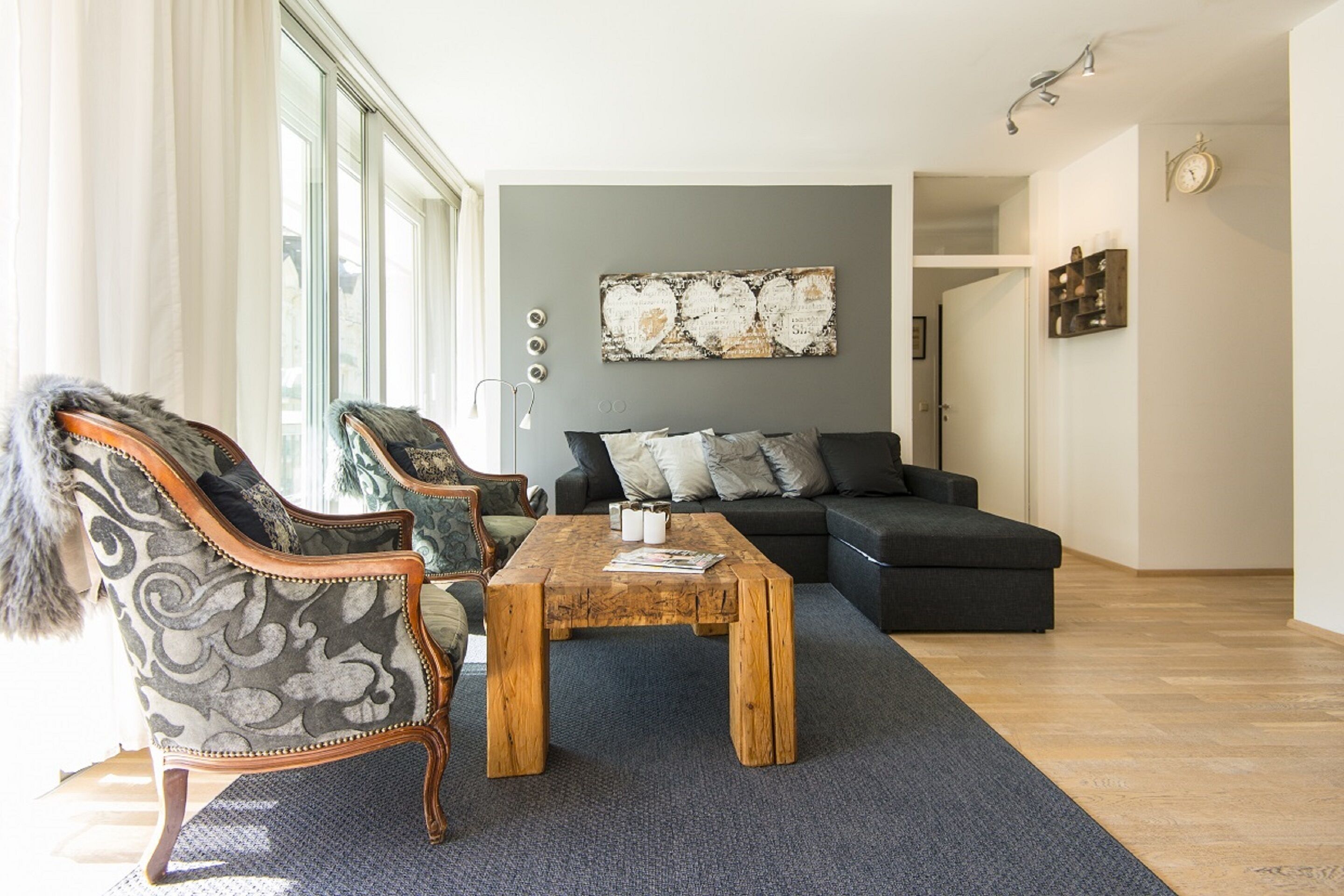 A living room with a sofa, two armchairs, a coffee table, and a large abstract painting on the wall.