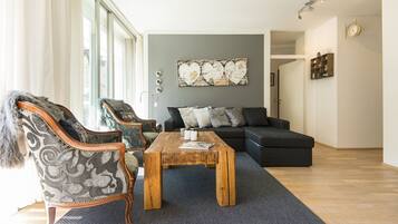 A living room with a sofa, two armchairs, a coffee table, and a large abstract painting on the wall.