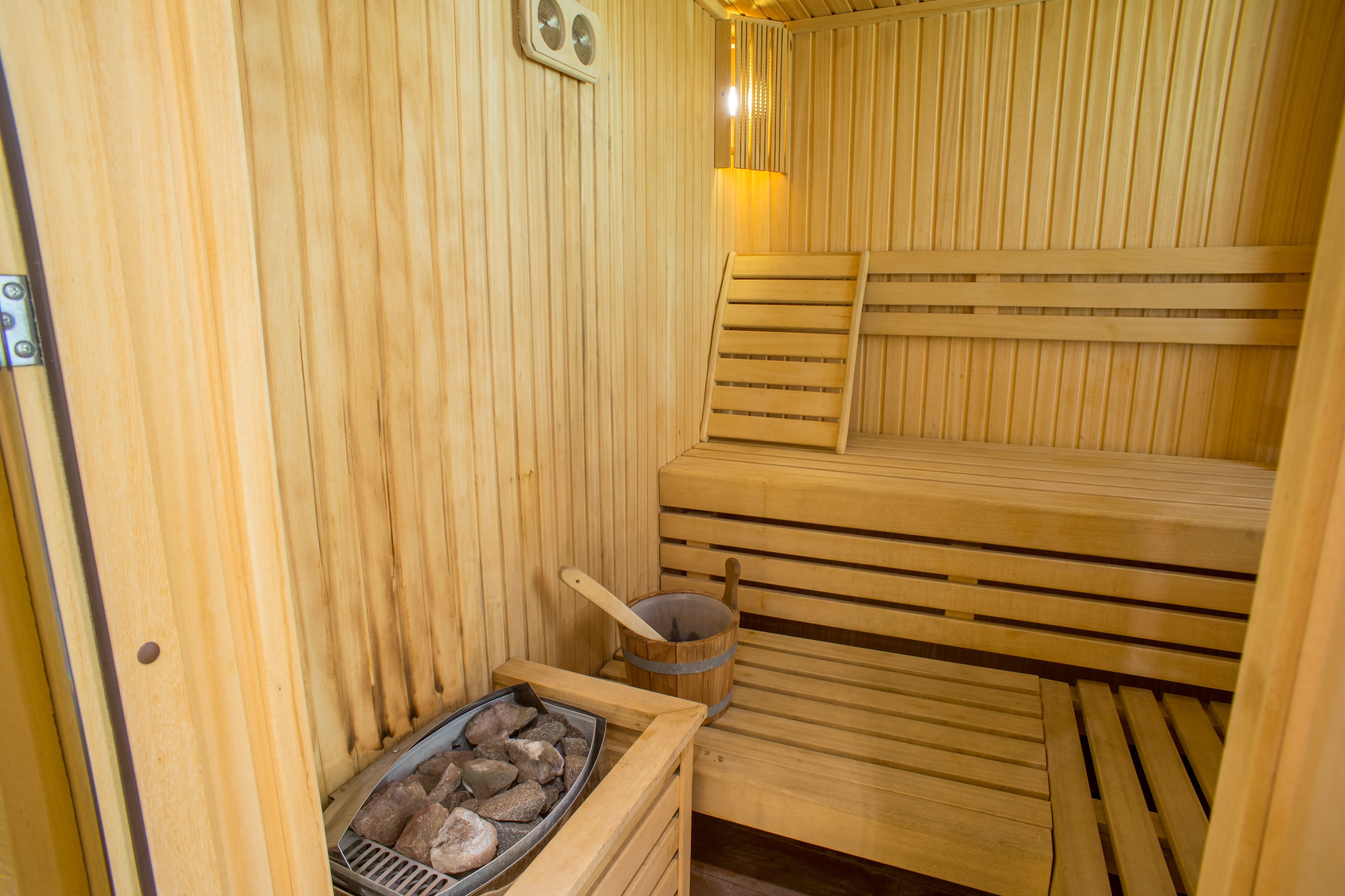 Una sauna de madera con bancos y un cubo de piedras.