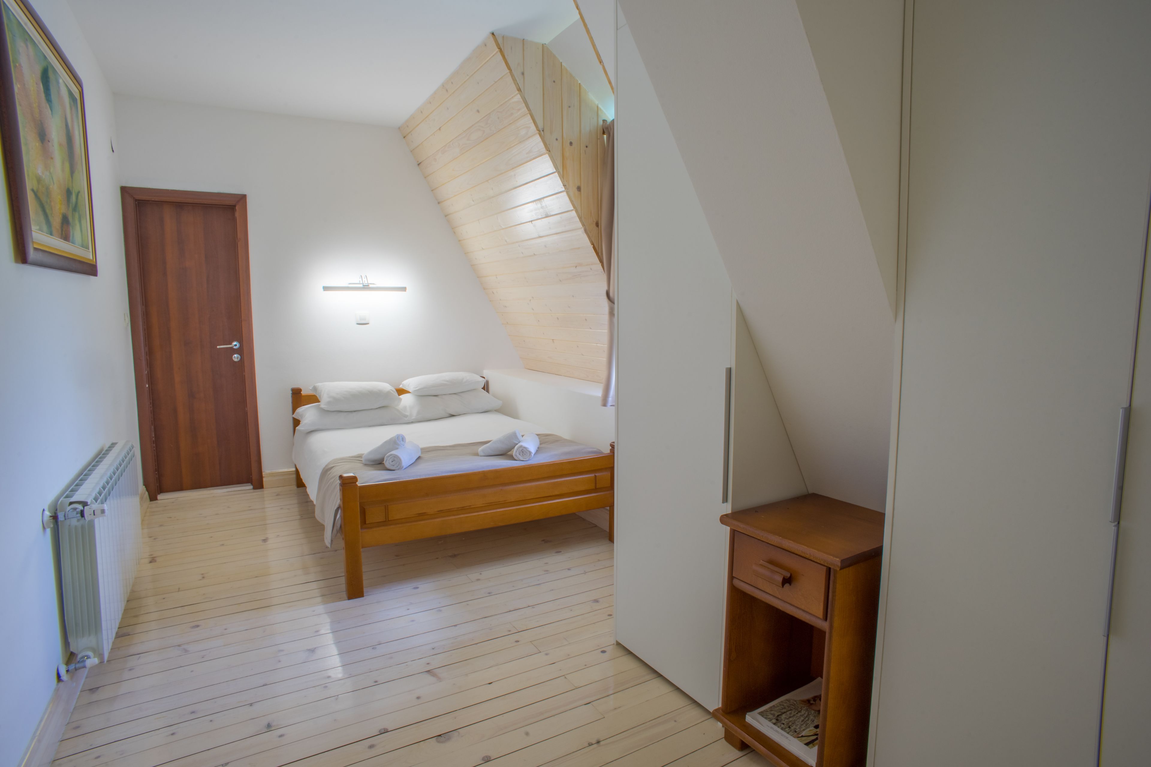 Une chambre à coucher avec un lit en bois, une table de chevet et un plafond en pente.