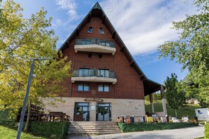 Un edificio de madera de varios pisos con un balcón en el segundo nivel, un letrero que dice 'POLAR STAR', y una pequeña zona de estar al aire libre con mesas y sillas.