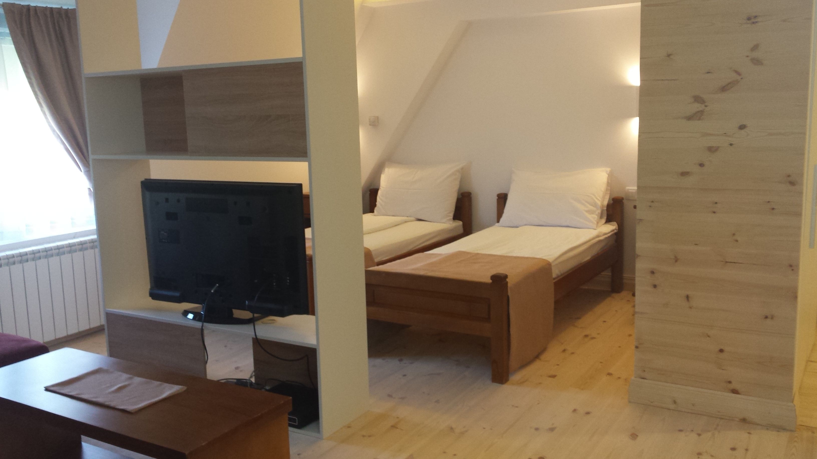 A bedroom with a bed, a desk, and a television.