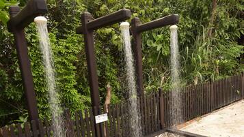 Un élément décoratif aquatique doté de plusieurs jets d’eau, entouré d’une clôture en bois et agrémenté d’un sol à motifs.