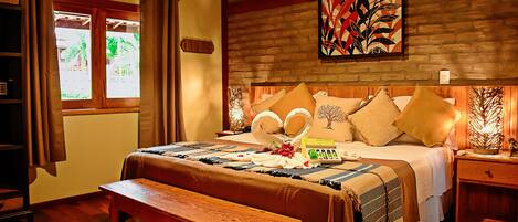 A well-lit bedroom with a wooden bed, a bench, and a nightstand with a lamp.