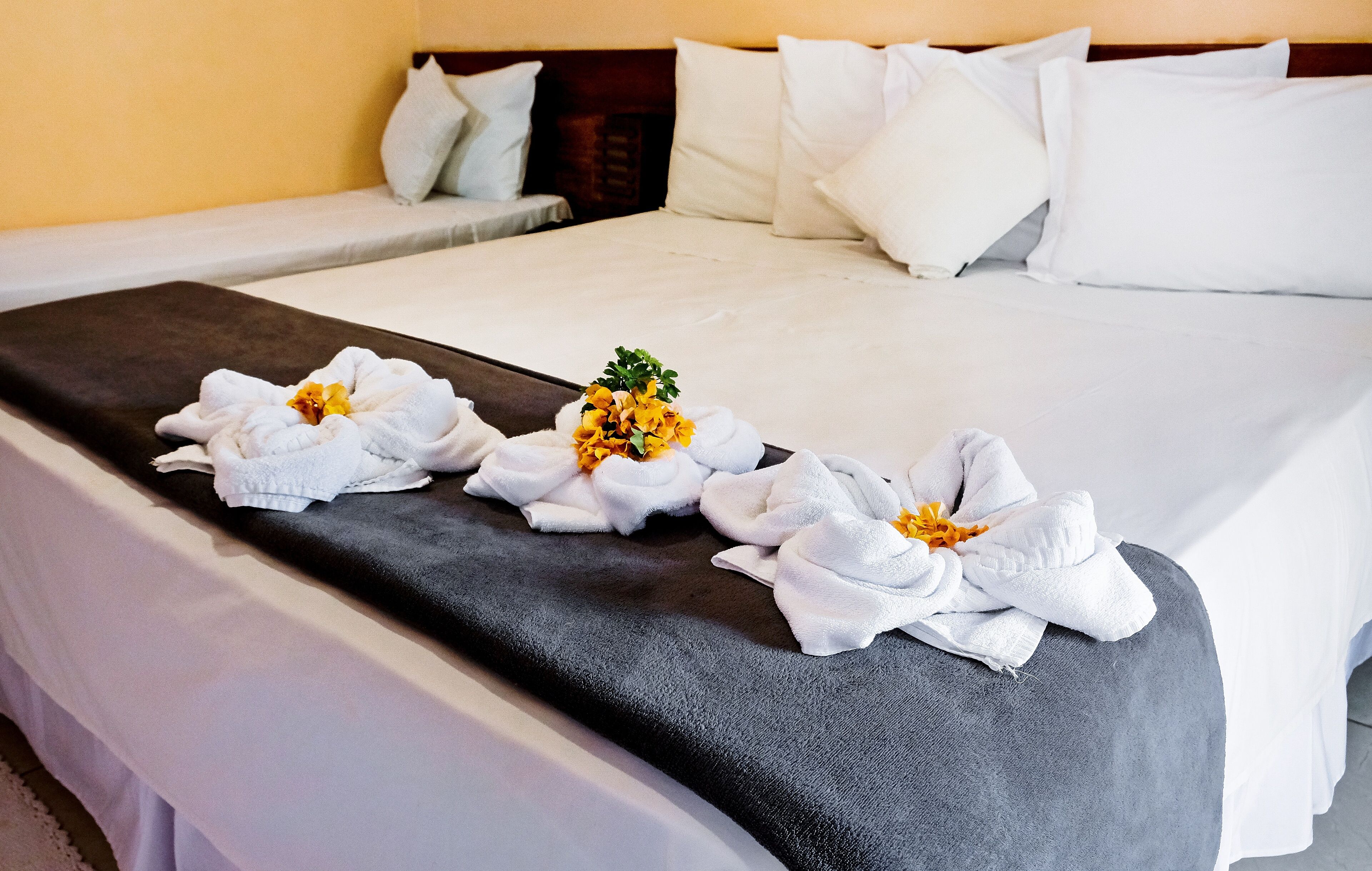 A neatly made bed with white linens and a dark gray bed runner.
