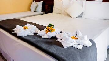 A neatly made bed with white linens and a dark gray bed runner.