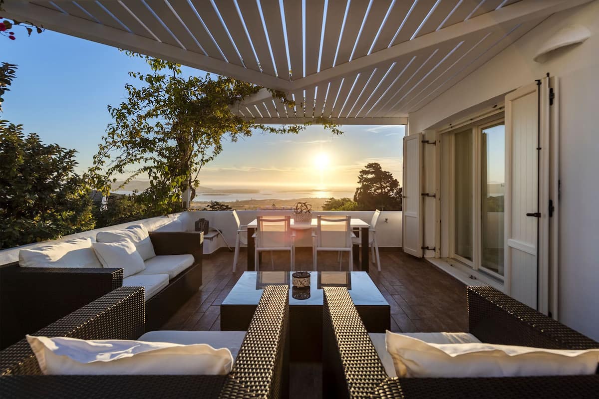 Un espacio de estar techado al aire libre con una mesa y sillas, con vistas a un paisaje pintoresco.
