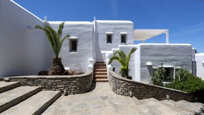 Edifici emblanquit amb escales de pedra que condueixen a una porta, palmeres i un cel blau clar.