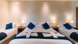 A hotel room with three beds, each with white and blue bedding, and two bedside lamps. - Pousada La Toscana (Campos do Jordão)