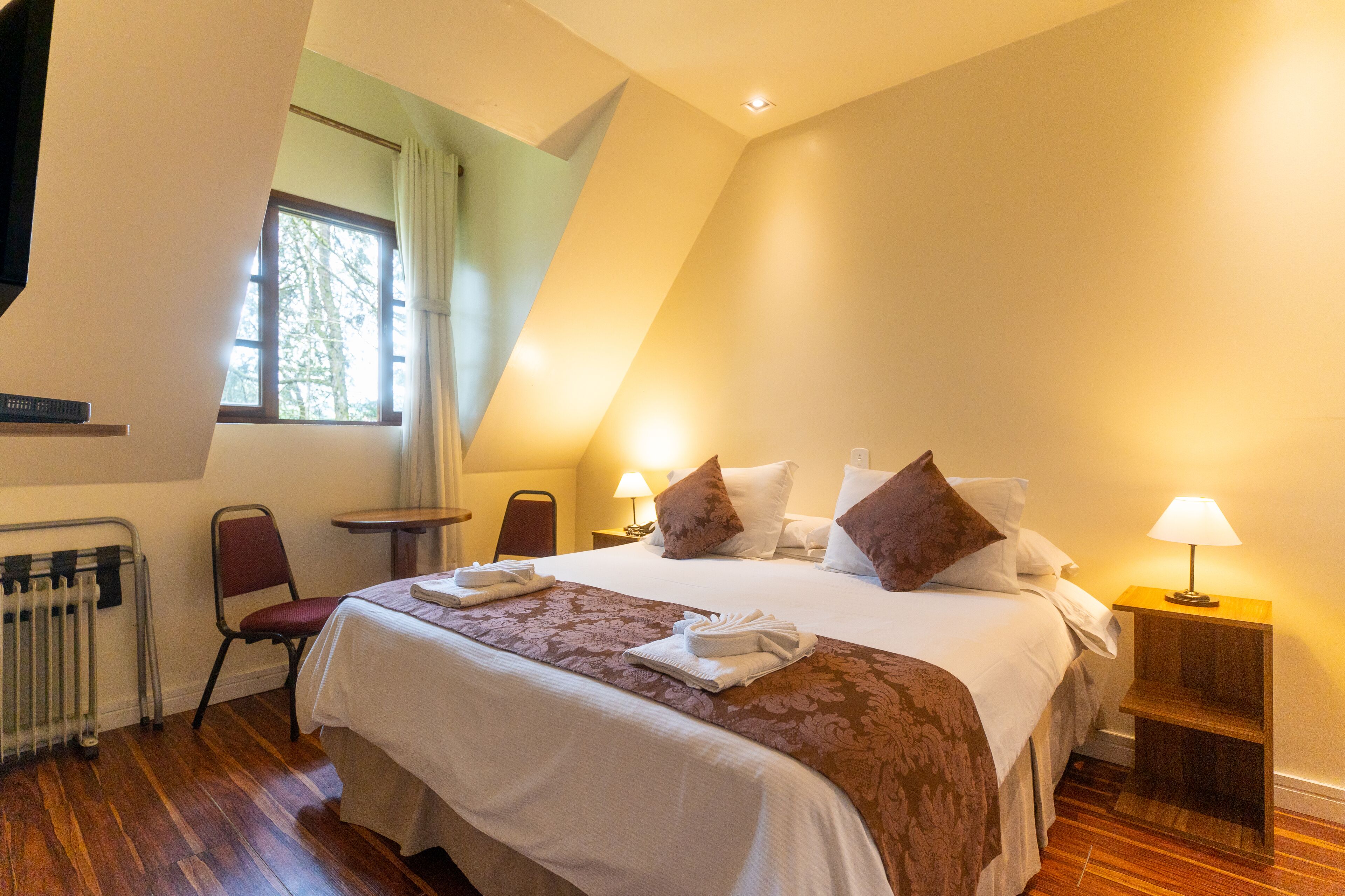 Ein Hotelzimmer mit einem großen Bett, einem Sessel, einem kleinen Tisch und einer Lampe.