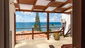 A balcony with a view of the ocean, a potted plant, and a wooden bench. - Pousada Ilha da Saudade (Cairu)