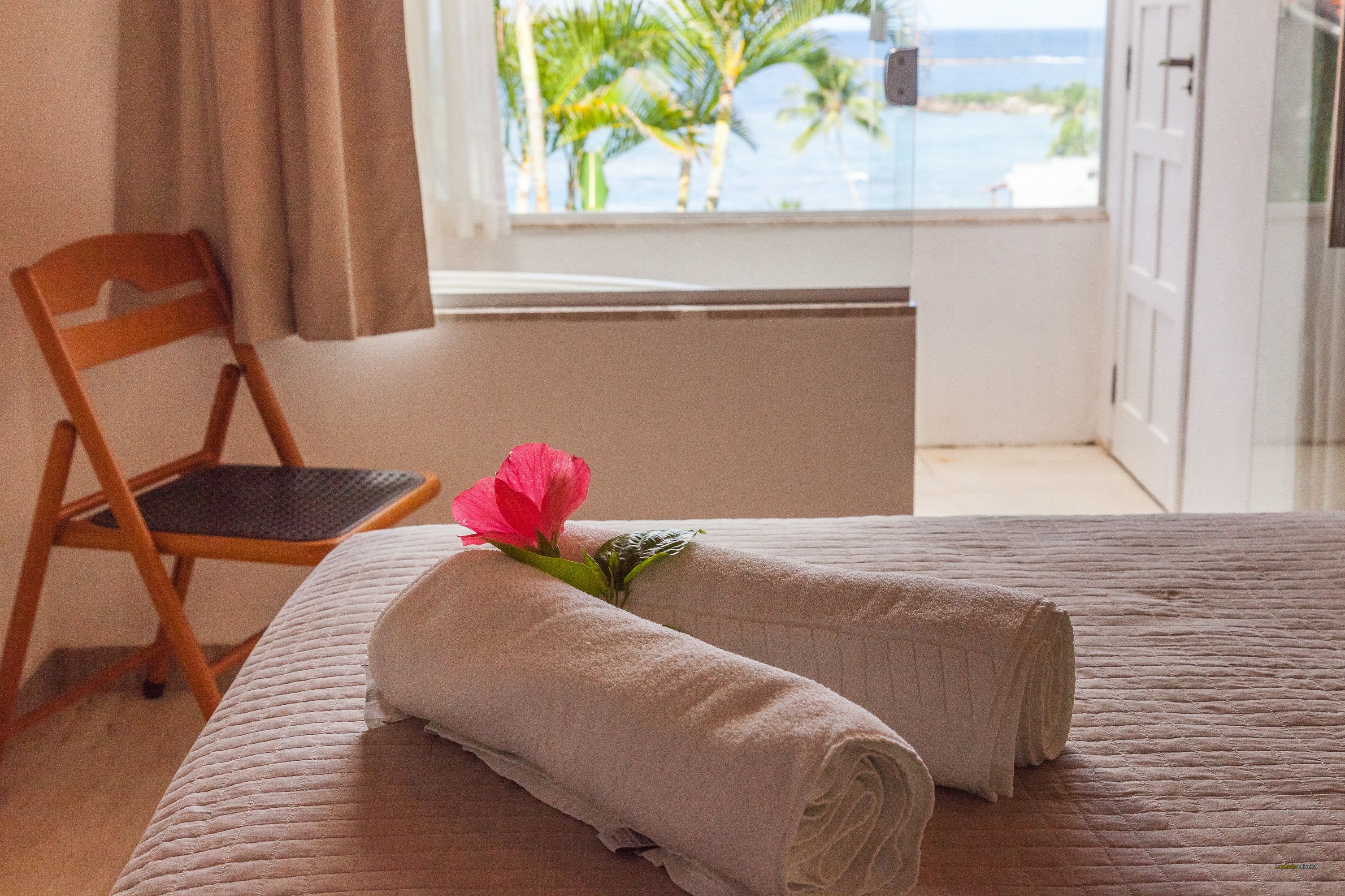 A hotel room with a bed, a chair, and a view of the ocean.