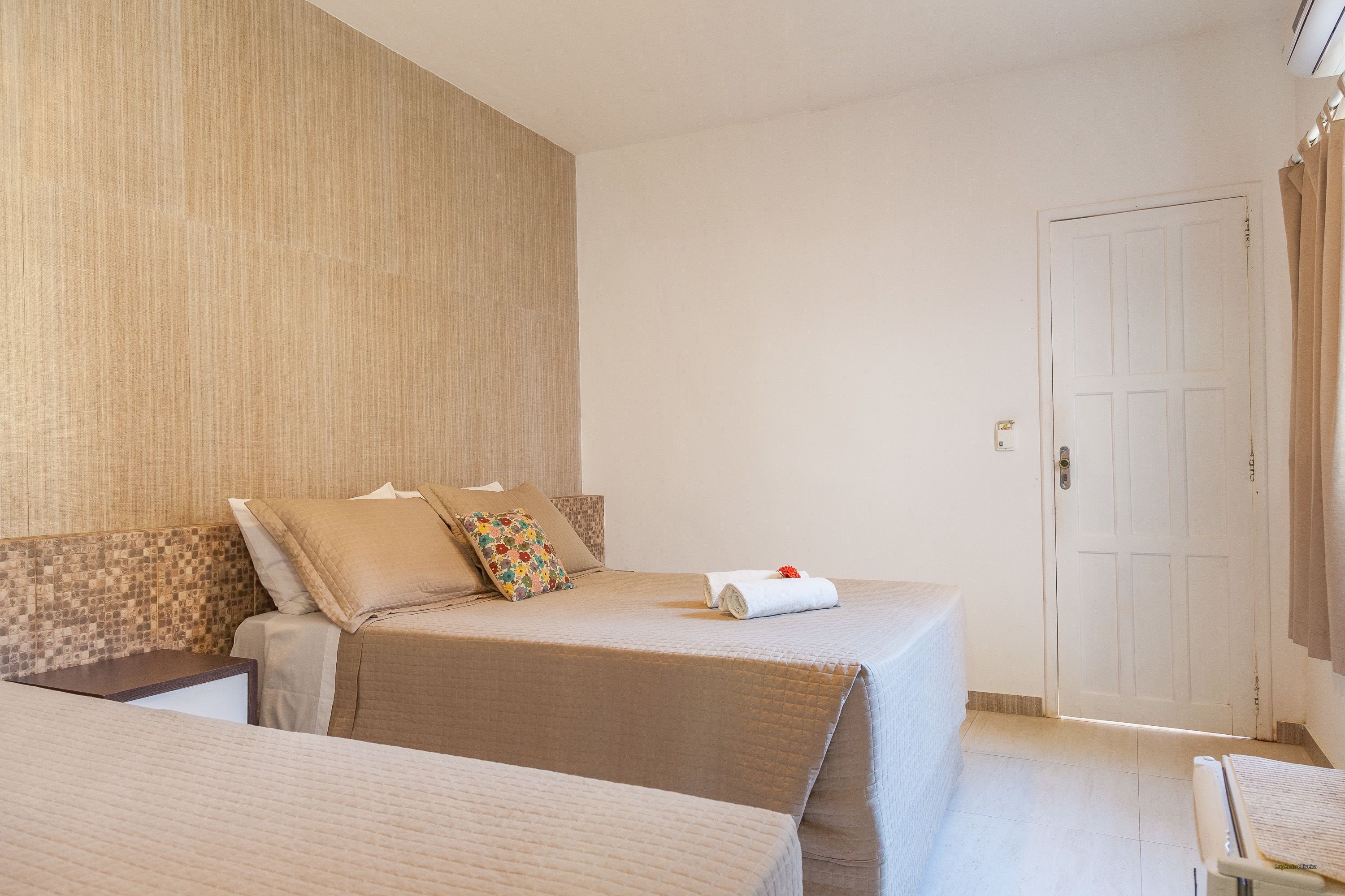 A hotel room with two beds, a wooden headboard, a white door, and a small table.
