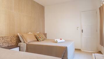 A hotel room with two beds, a wooden headboard, a white door, and a small table.