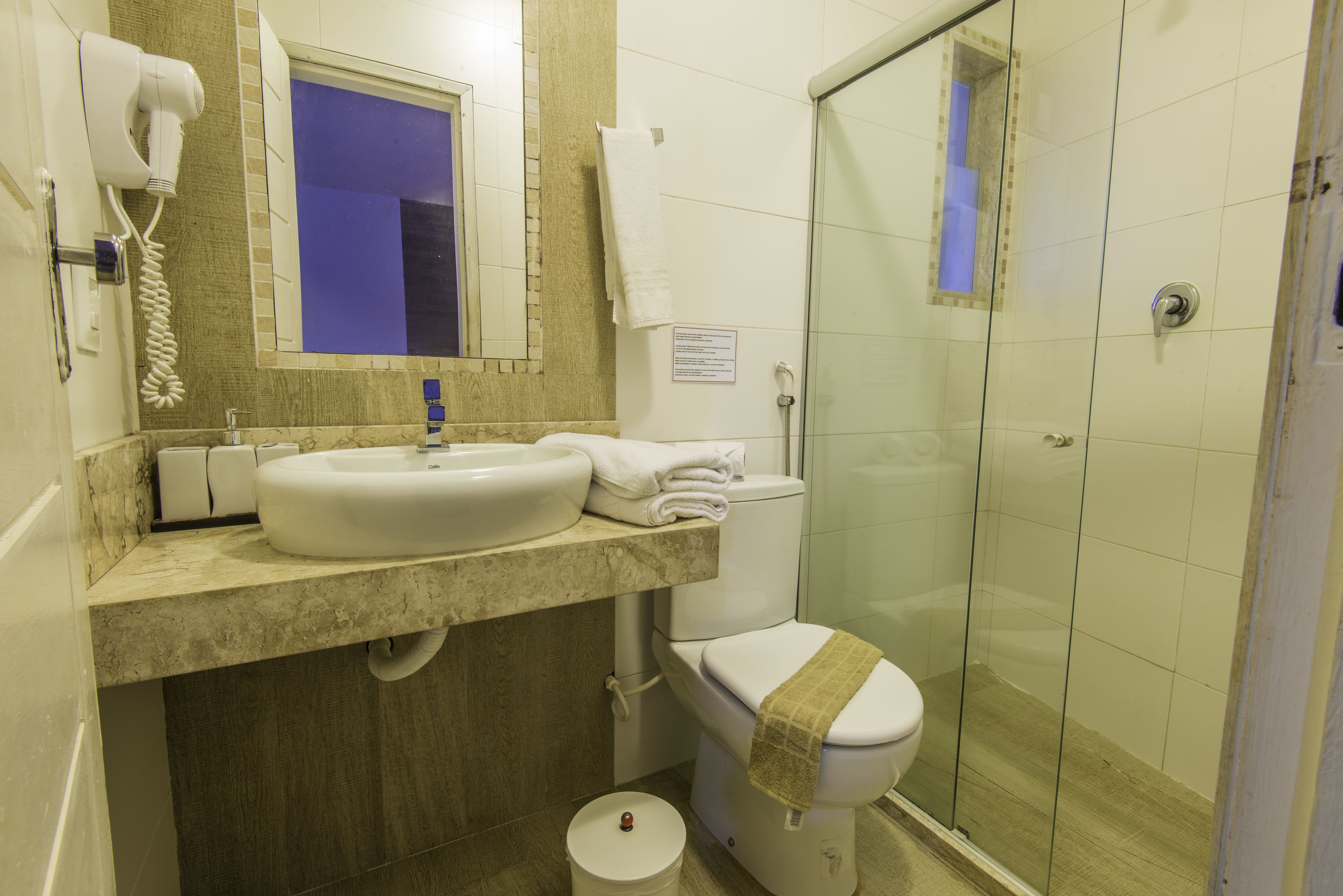 Un baño con lavamanos, inodoro y cabina de ducha de vidrio.