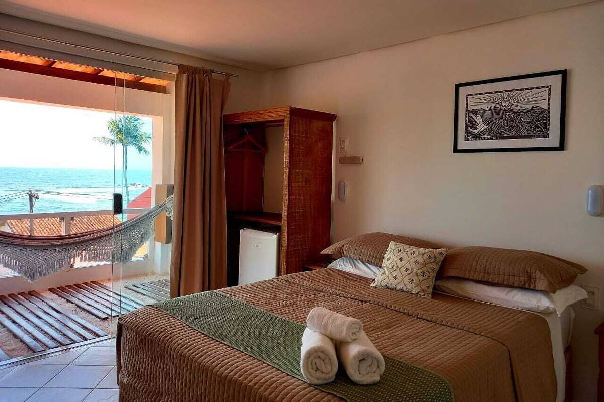 Habitación de hotel con cama, hamaca y vista al océano.