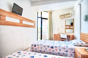 Habitación de hotel con dos camas, un escritorio, una silla, un televisor y una ventana con cortinas.