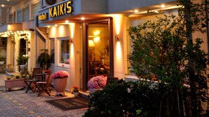 A hotel named "Hotel Kaikis" with a balcony, potted plants, and outdoor seating. - Hotel Kaikis (Kalabaka)