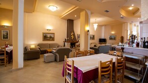 A spacious living area with a dining table, sofas, and a fireplace. - Hotel Kaikis (Kalabaka)