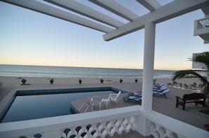 Área da piscina com espreguiçadeiras e vista para a praia.