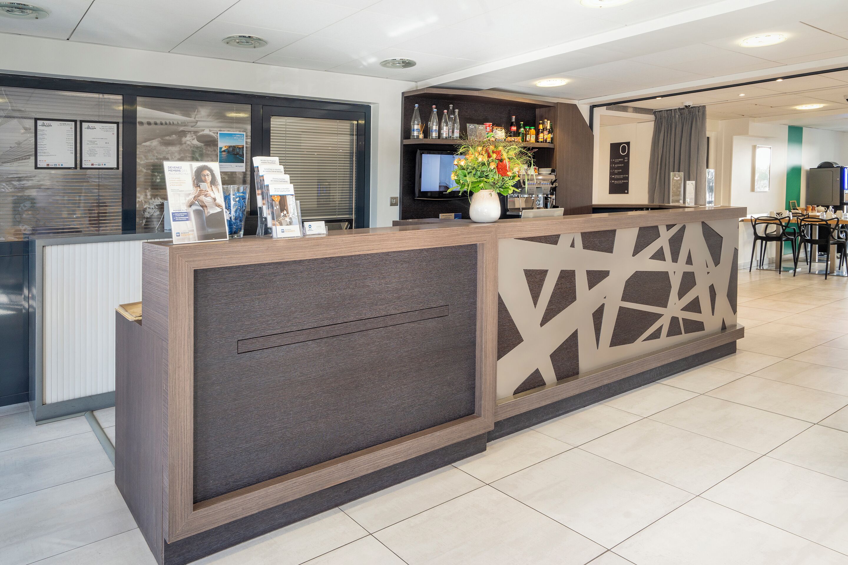 A reception area with a modern counter, a television, and a bar area with bottles and glasses.