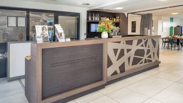 A reception area with a modern counter, a television, and a bar area with bottles and glasses.