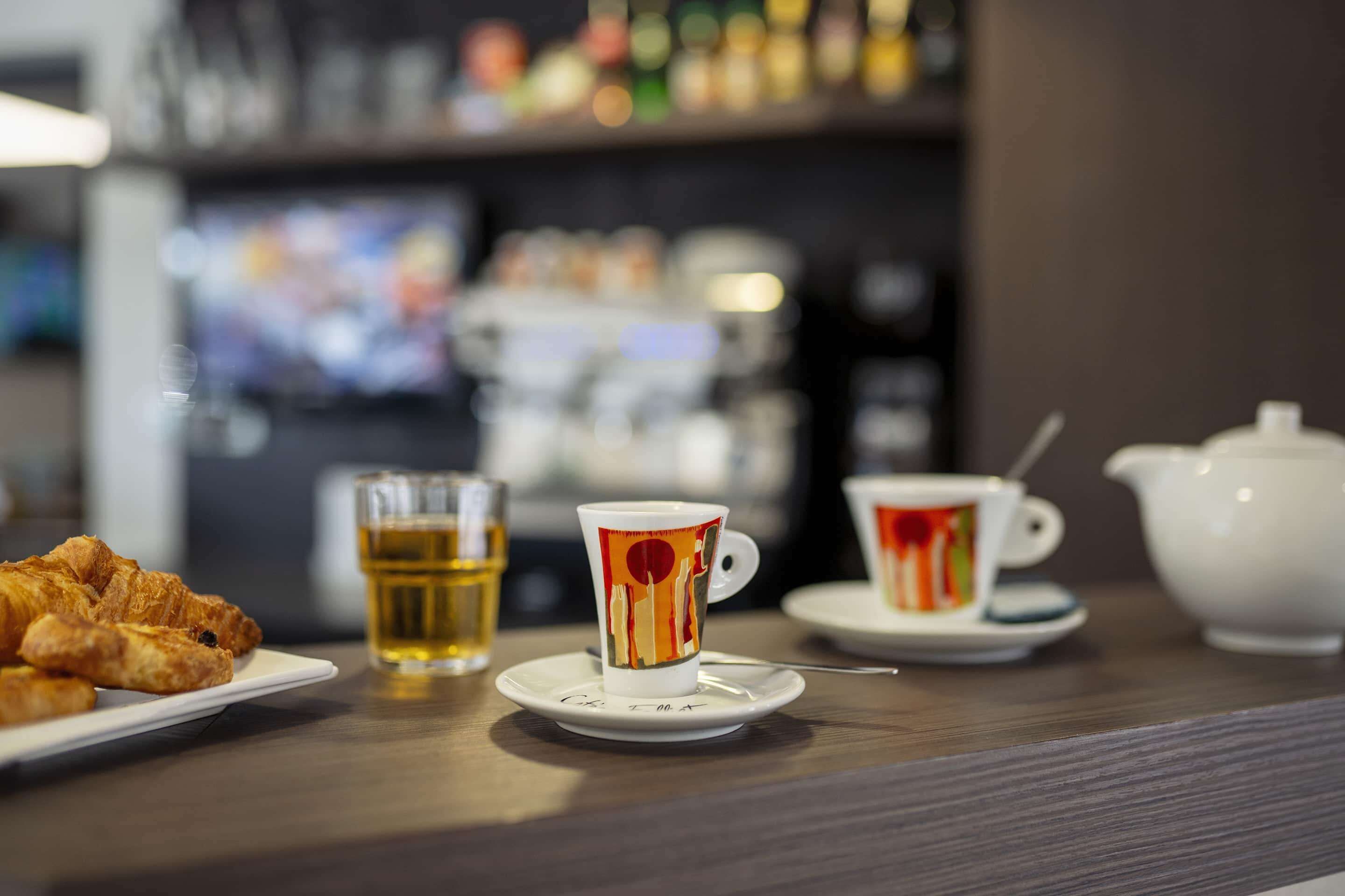 A breakfast setting with croissants, a cup of tea, and a teapot on a table.