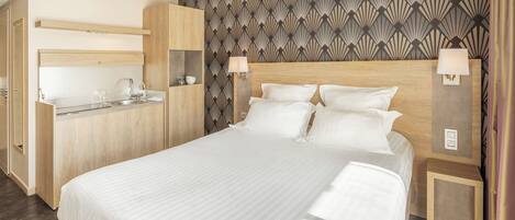 A modern hotel room with a large bed, a wooden desk, and a patterned wallpaper.