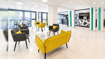 Egy modern belső tér, pihenőhelyekkel, recepcióval és bárral.
