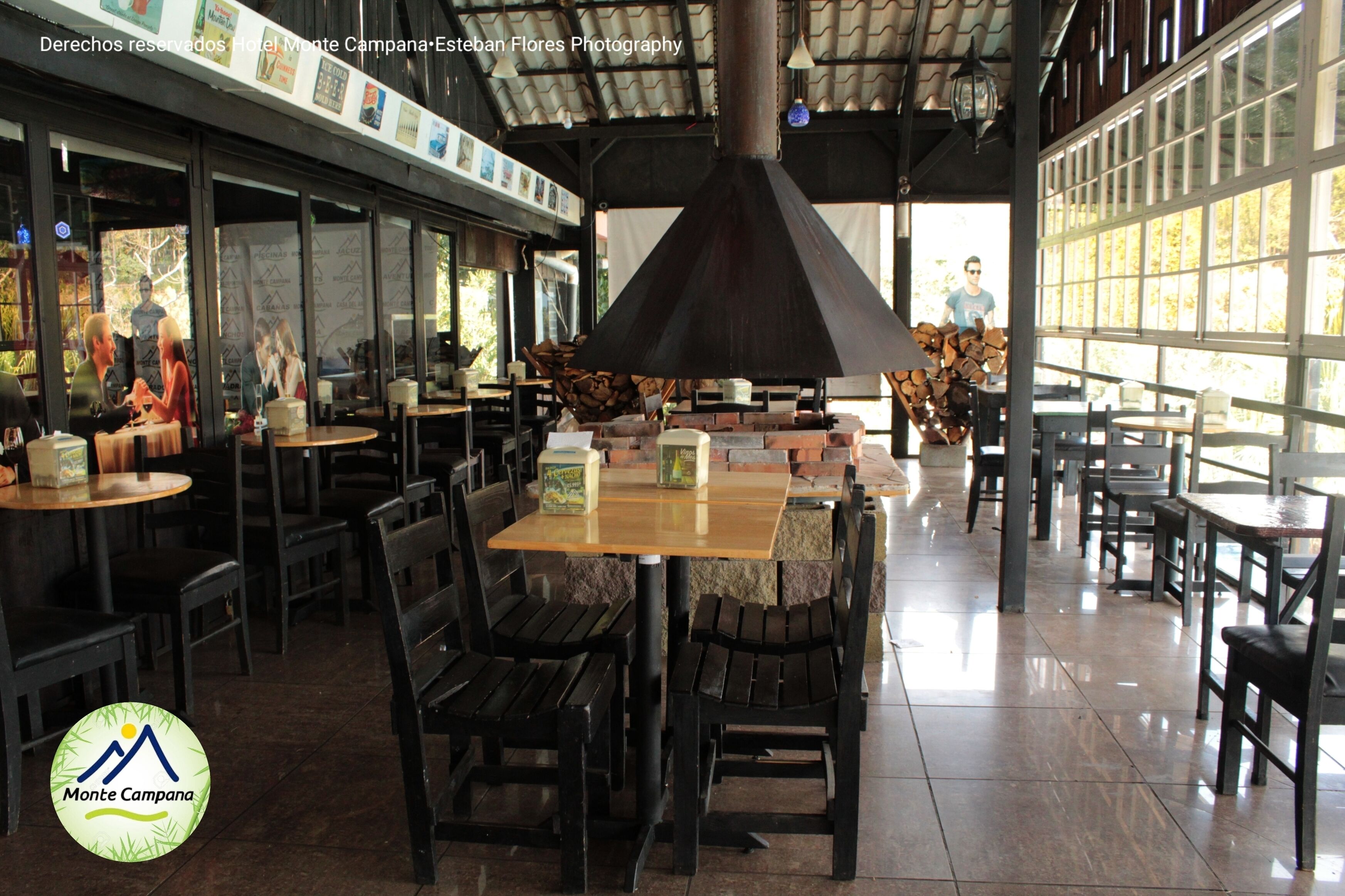 Un restaurante con mesas y sillas, una chimenea grande y vistas al exterior.