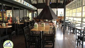 Un restaurante con mesas y sillas, una chimenea grande y vistas al exterior.