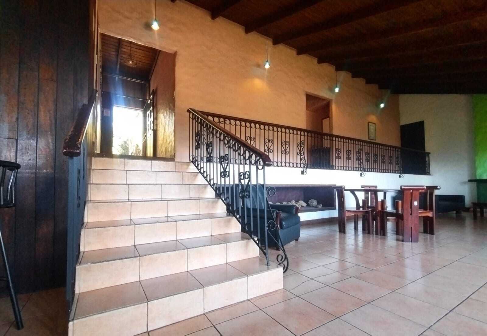 A staircase with a black railing leading to a landing area with a sofa and chairs.