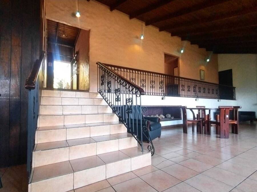 A staircase with a black railing leading to a landing area with a sofa and chairs.