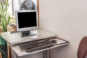 A computer desk with a monitor, keyboard, and mouse.